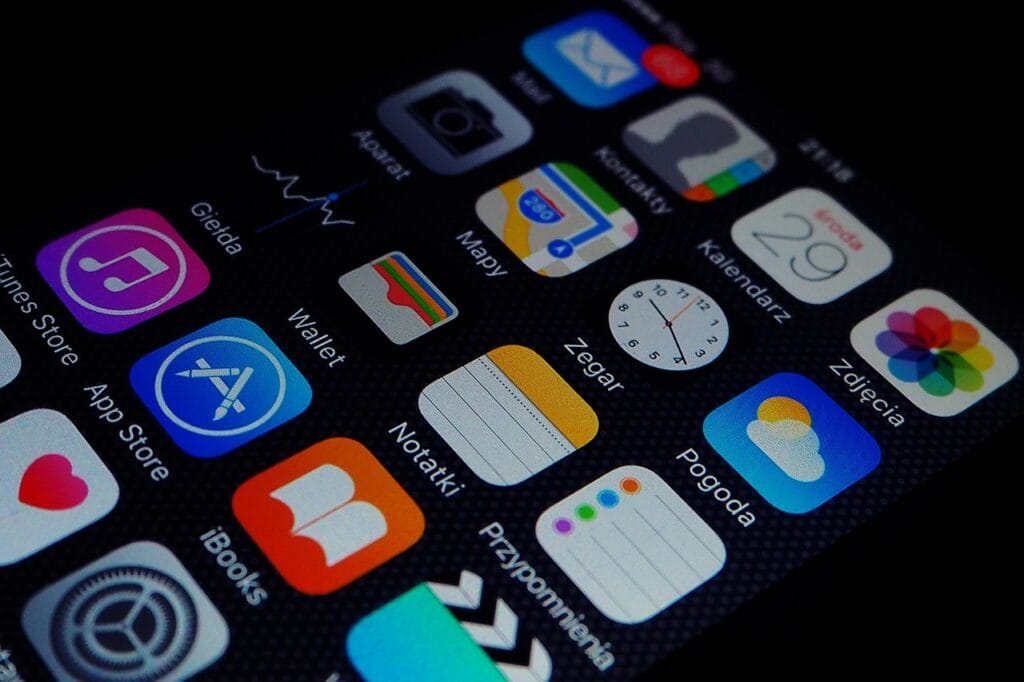 Smartphone screen showing various default iOS app icons, including App Store, iTunes, Wallet, Calendar, and Photos.
