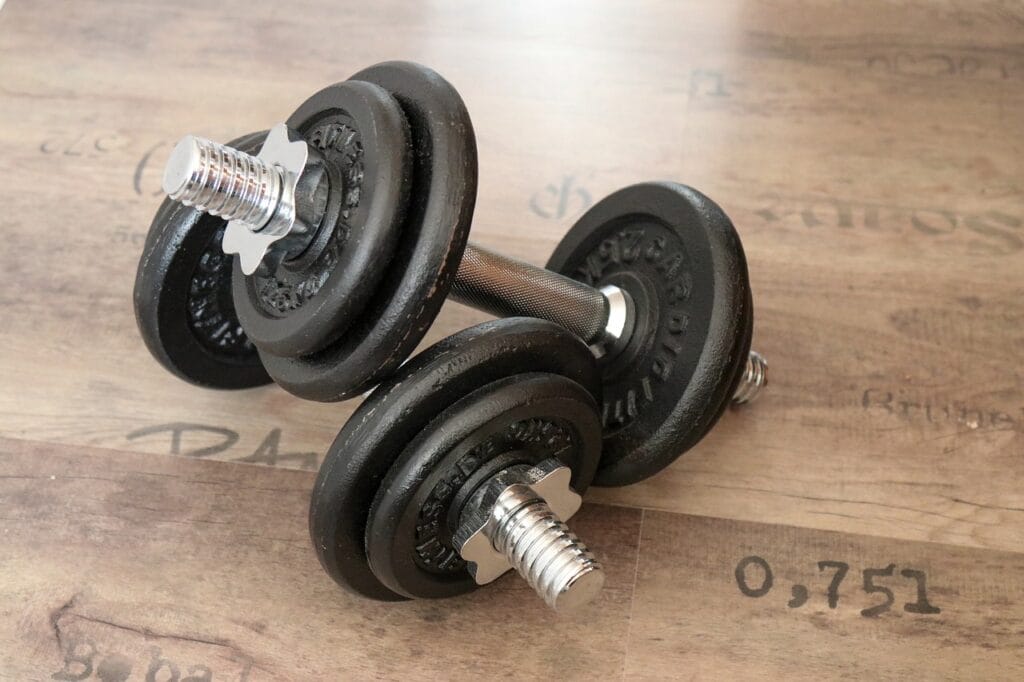Pair of adjustable dumbbells resting on a wooden surface.