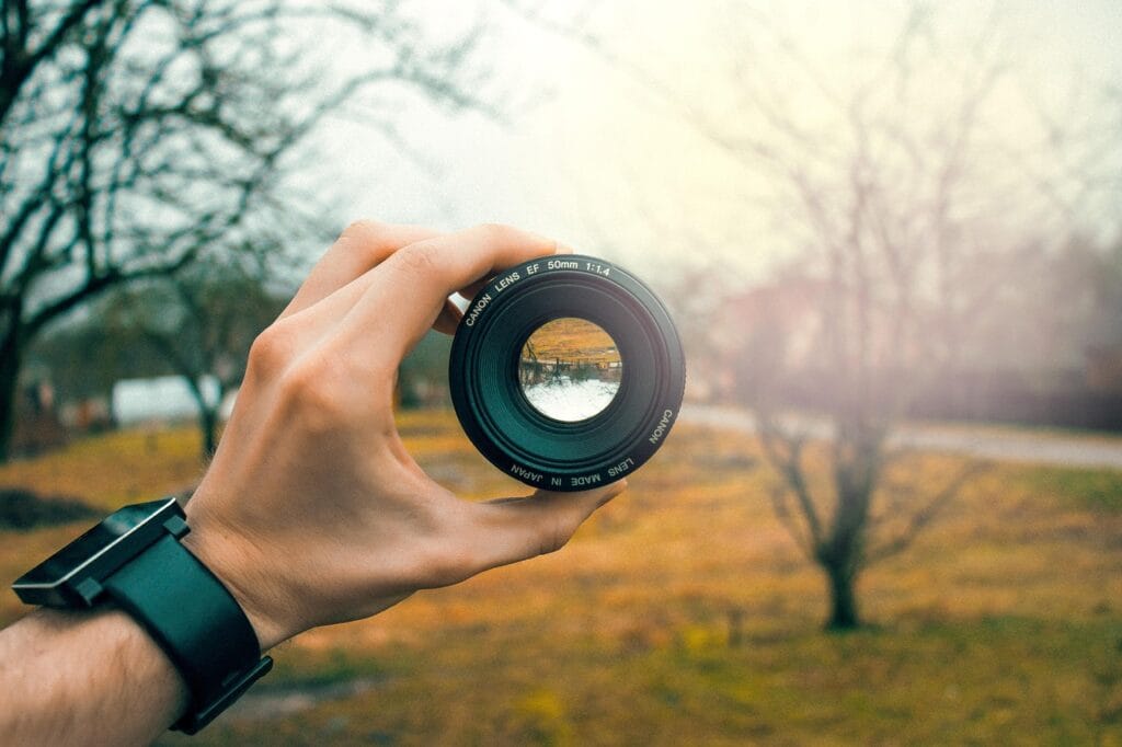 Person holding a camera lens, symbolizing best smart home devices for home security.