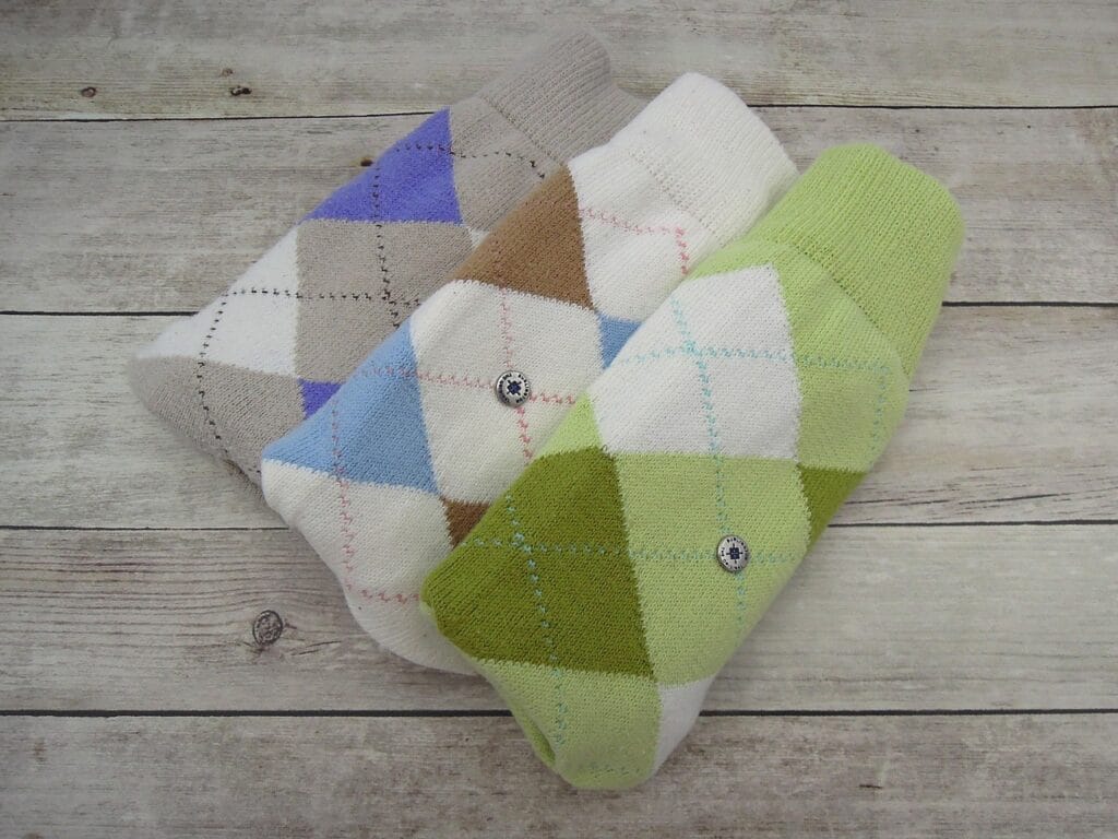 Three pairs of sustainably made argyle patterned socks neatly folded on a wooden background